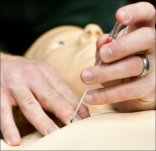 Needle is inserted into chest of dummy.