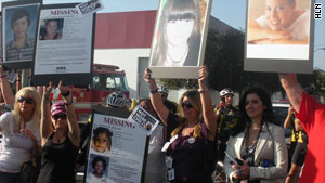 Diena Thompson, in dark shirt, holds up a poster of her slain daughter, Somer. A man awaits trial for murder.